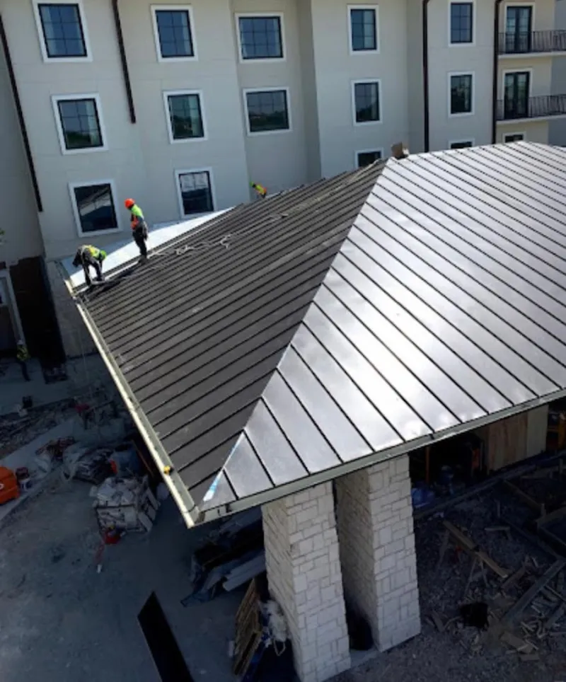 Crew installing standing seam metal roof panels on a commercial project in DeWitt